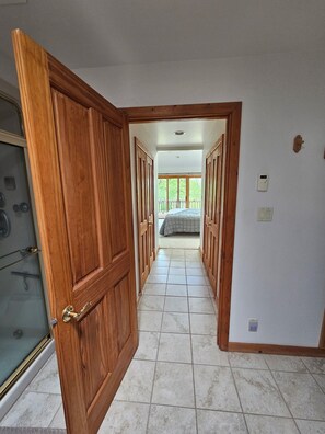 Ein Flur mit Holztüren, die in ein Schlafzimmer mit Bett und Balkon führen.