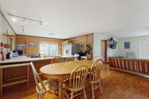 A kitchen with wooden cabinets, a dining table with chairs, a refrigerator, and a television. - Cute cottage with fast WiFi & full kitchen - 1 mile to downtown & next to Acadia (Bar Harbor)