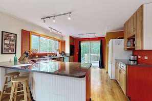 Eine moderne Küche mit einer zentralen Kochinsel, Holzschränken und einem großen Fenster.