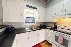 A kitchen with white cabinets, a double sink, a stove, and a toaster. - Upper Corbel - Charming upstairs duplex with fast WiFi, partial AC, & walkable location (Bucksport)