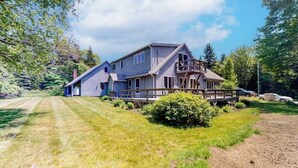 Een ruime woning met terras, omgeven door een verzorgd gazon en bomen.