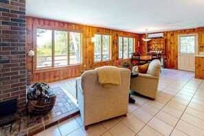 A wooden interior with two sofas, a fireplace, and large windows. - Dog-friendly beach house with WiFi, private washer/dryer, deck, beautiful views (Bristol)
