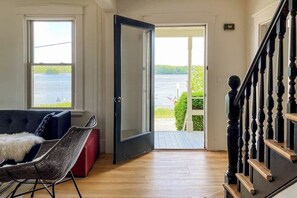 Una habitación con vistas a un cuerpo de agua, una puerta que da al exterior, una escalera y un sofá con una manta mullida.