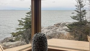 A room with a large window overlooking a rocky shoreline and the sea. - Spectacular oceanfront retreat with amazing views, sunroom & washer/dryer (Georgetown)