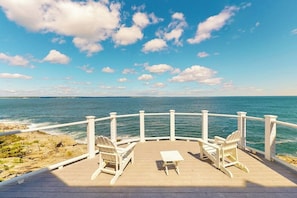 A wooden deck with white chairs and a table overlooking the ocean. - Spectacular oceanfront retreat with amazing views, sunroom & washer/dryer (Georgetown)
