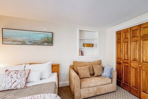 Ein Schlafzimmer mit einem Bett, einer Schlafcouch, einem Holzschrank und einem Regal mit Büchern und einem Korb.