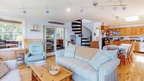 Uma sala de estar moderna com um sofá, uma mesa de centro de madeira e um espaço de jantar com mesa e cadeiras.