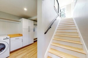 A laundry area with a washing machine, cabinets, and a wooden counter.