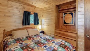Een houten kamer met een bed, een raam met gordijnen en een deur met decoratief paneel.