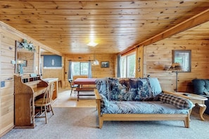 A wooden cabin interior with a sofa, a desk, and a dining table. - Lake front home with privately shared dock for the homes in this complex (Greenville)