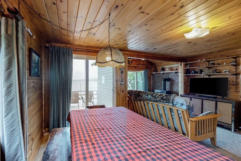 L’intérieur d’une cabane comprend un lit, un canapé, un téléviseur et une cheminée.