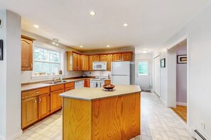 A kitchen with wooden cabinets, a central island, a microwave, and a refrigerator. - Idyllic waterfront home with furnished deck, grill, sweeping views & private W/D (Waldoboro)