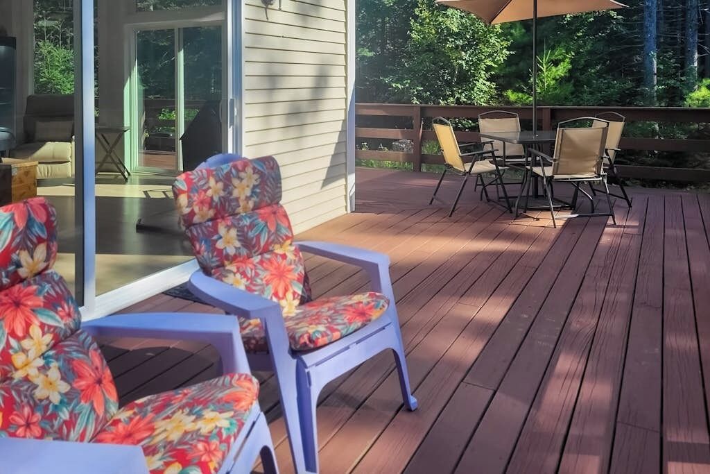 Een terras met buitenmeubilair, waaronder stoelen en een tafel, en een glazen deur die leidt naar een binnenruimte.