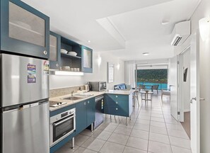Una cocina moderna con electrodomésticos de acero inoxidable, horno empotrado y diseño de armarios azules.