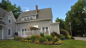 A two-story house with a front porch, a chimney, and a well-maintained garden. - Gorgeous water-view home & attached apartment (Camden)