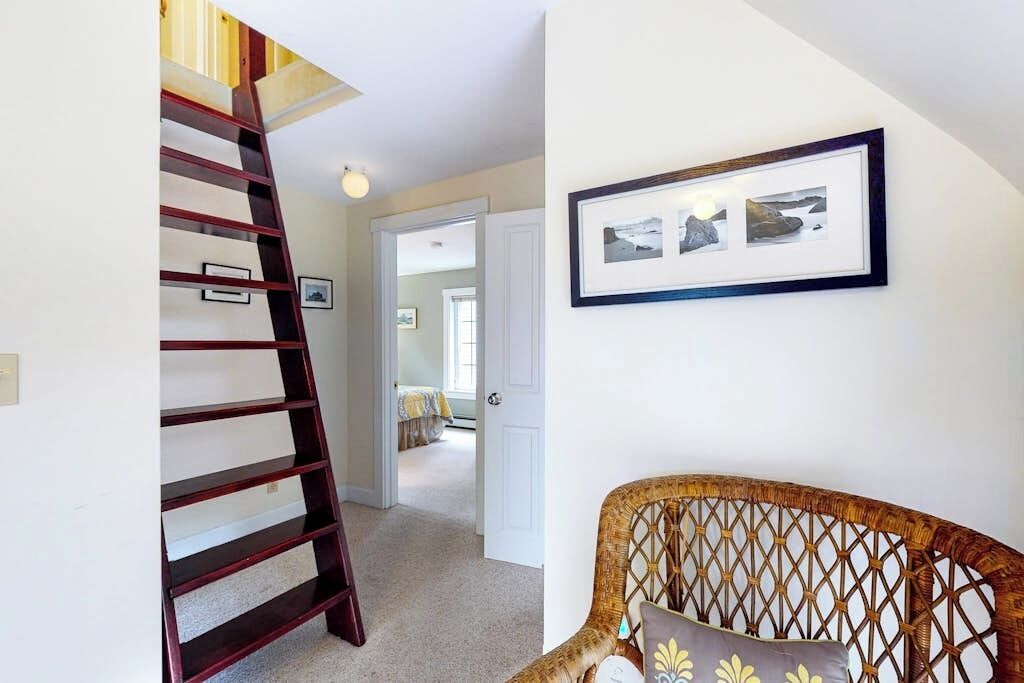 Eine Treppe, ein Korbstuhl und ein gerahmtes Bild an der Wand.