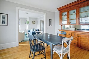 Un comedor con mesa y sillas, una cocina con armarios de madera y una sala de estar con sofá y planta.