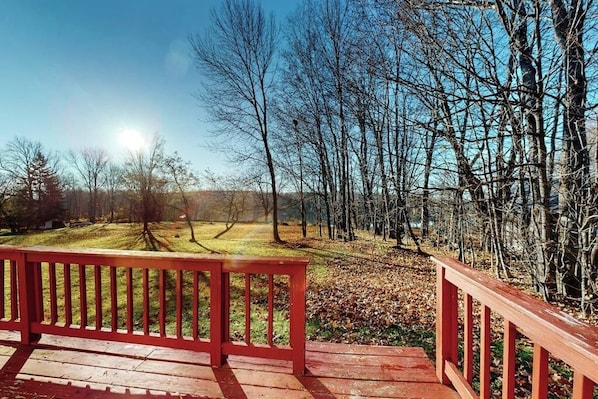 Eine Holzterrasse mit roter Geländer, mit Blick auf bewaldetes Gebiet.