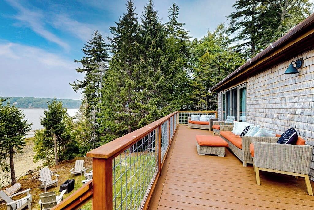 A deck with outdoor furniture, a view of the lake, and a building with a brick exterior.