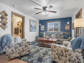 A living room with a ceiling fan, a sofa, two armchairs, a coffee table, and a rug. - WALK TO EVERYTHING, REMODELED, BEAUTIFUL NEIGHBORHOOD, LARGE YARD, AND FENCED! (Williams)