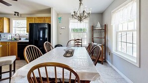 A kitchen with a dining table, chairs, a chandelier, and a refrigerator. - Charming cottage near the beach with balcony, deck, grill, fireplace - dogs OK (Georgetown)