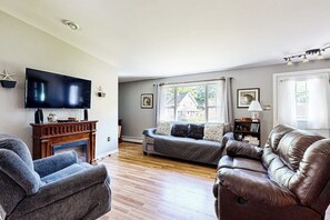 Una sala de estar con chimenea, televisor, sofá y un sillón de cuero.
