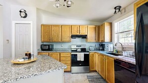 A kitchen with granite countertops, wooden cabinets, a stainless steel oven, a microwave, and a refrigerator. - Charming cottage near the beach with balcony, deck, grill, fireplace - dogs OK (Georgetown)