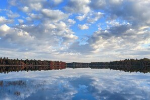 A calm lake with a reflection of trees and sky.