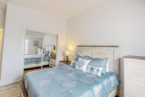 A bedroom with a bed, a nightstand, a dresser, a mirror, and a door leading to another room. - Oceanfront, dog-friendly condo with Boothbay Harbor views & prime location (Boothbay Harbor)