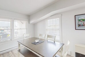 A modern dining area with a table, chairs, and large windows with blinds. - Oceanfront, dog-friendly condo with Boothbay Harbor views & prime location (Boothbay Harbor)