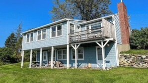 A two-story house with a balcony, a stone foundation, and a chimney. - Charming abode with water views, updated kitchen, & internet - dog-friendly (Castine)