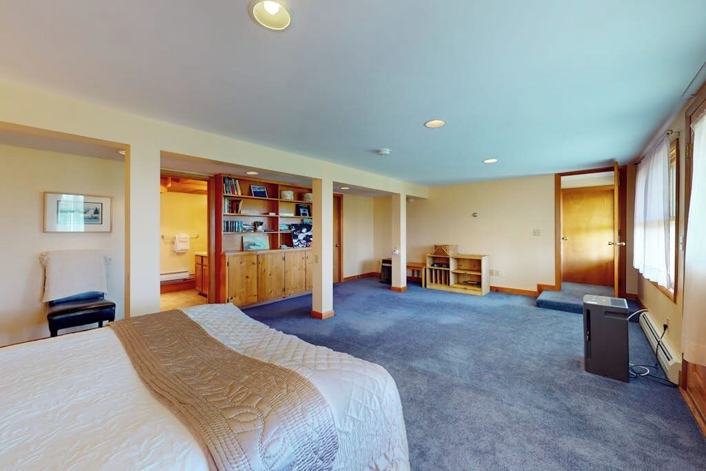 Een hotelkamer met een groot bed, een bureau, een boekenplank en een zithoekje.