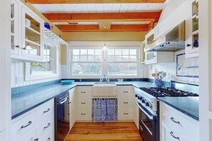 Eine Küche mit Holzbalken, einer Mittelinsel, einem eingebauten Ofen und einem Fenster mit Blick auf eine Stadtlandschaft.