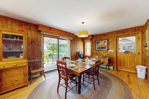 Una sala da pranzo in legno con un tavolo rotondo, sedie e un lampadario.