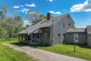 Una casa di legno rustica con veranda, camino e una bandiera.