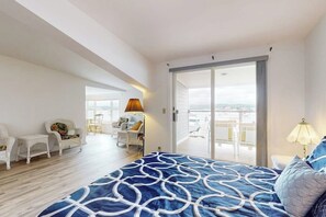 Ein Schlafzimmer mit einem großen Bett, einem Balkon mit Blick und einer Sitzecke mit Sesseln.