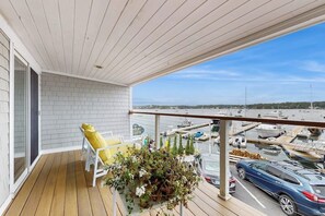Ein Balkon mit weißem Stuhl, einer Topfpflanze und Blick auf eine Marina mit Booten.