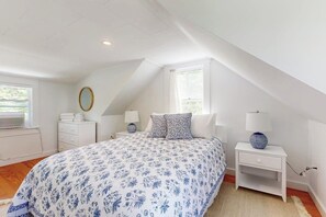A bedroom with a large bed, a bedside table with a lamp, a dresser, and a window. - Tranquil Seaside Cottage with Spectacular Views, Wifi & Washer/Dryer (Boothbay)