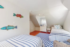 Un dormitorio con dos camas, un aparador y una silla.