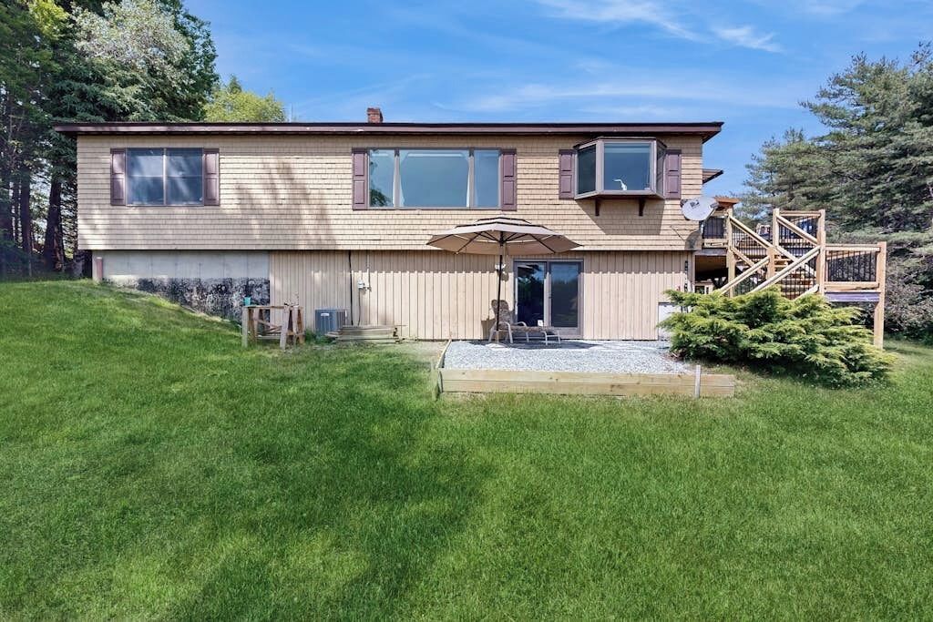 A two-story house with a front porch, a satellite dish, and a small deck.