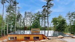 Een moderne houten chalet met schuin dak en grote ramen.