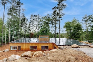 A modern cabin with a sloped roof, wooden exterior, and multiple windows. - Idyllic lakeside house with outdoor sauna, patio and firepit (Hope)