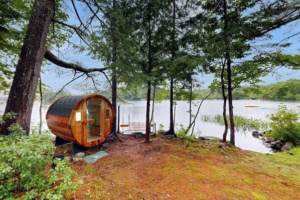 A wooden cabin by a lake surrounded by trees.