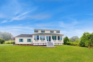 Ein zweistöckiges Haus mit Veranda, Auffahrt und gepflegtem Rasen.