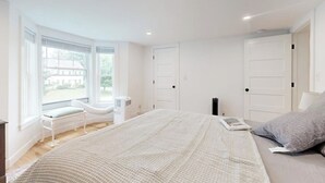 A bedroom with a large bed, a window seat, and a view of the outside. - Charming Camden Retreat with Front Porch, Deck and Wifi (Camden)