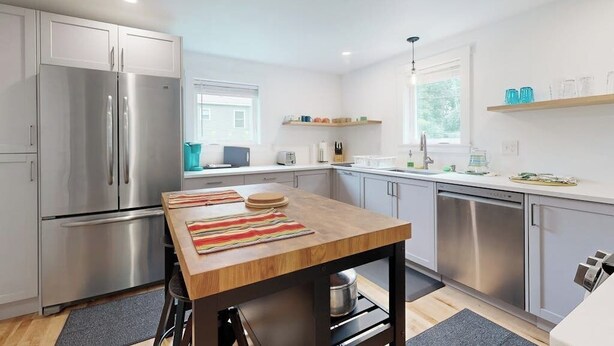 A modern kitchen with stainless steel appliances, a wooden table, and a window providing natural light. - Charming Camden Retreat with Front Porch, Deck and Wifi (Camden)