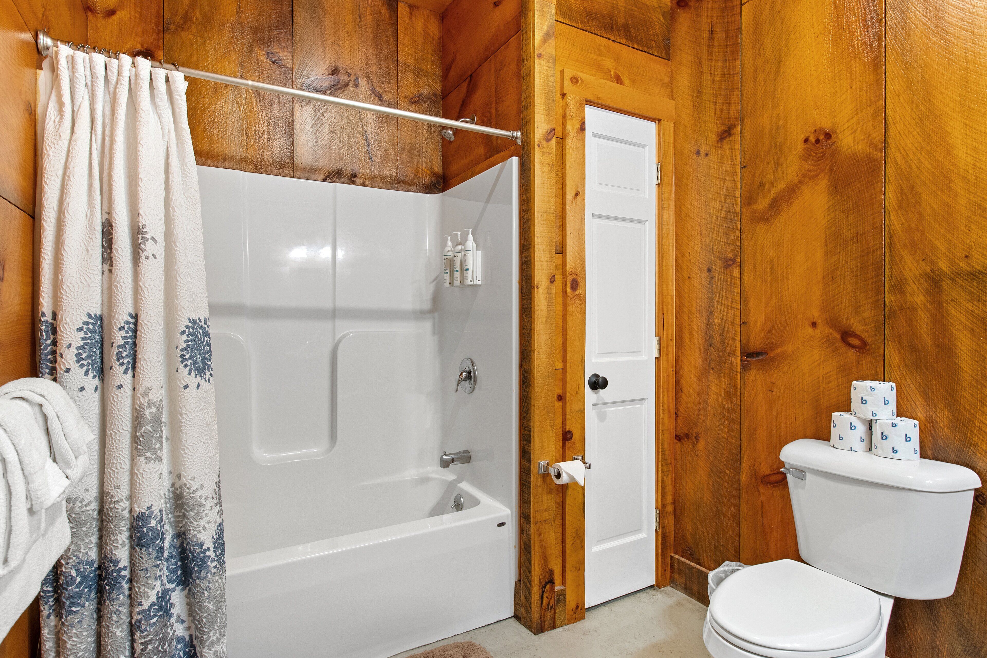 A bathroom with a bathtub, toilet, and shower curtain.