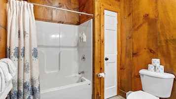 A bathroom with a bathtub, toilet, and shower curtain.