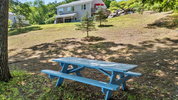 A picnic table in a grassy area with a house in the background.