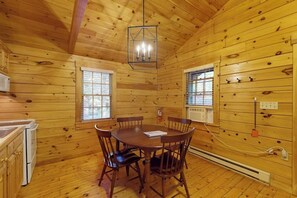 A wooden cabin interior with a dining table, chairs, a kitchen area, and a ceiling light fixture. - Create memories in this dog-friendly cabin w/fireplace, AC & near hiking (Northport)